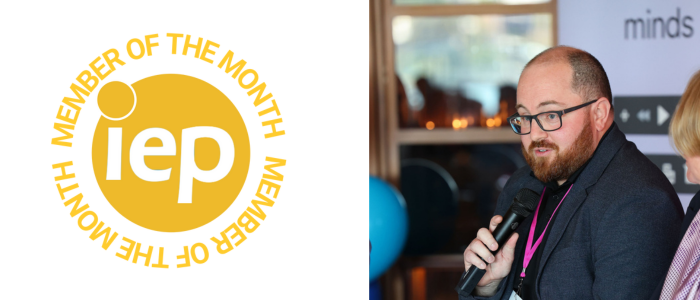 Man with a beard and glasses talking into a microphone